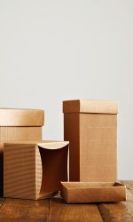 Unlabeled similar boxes of different shapes and sizes on an uneven wooden table isolated on white